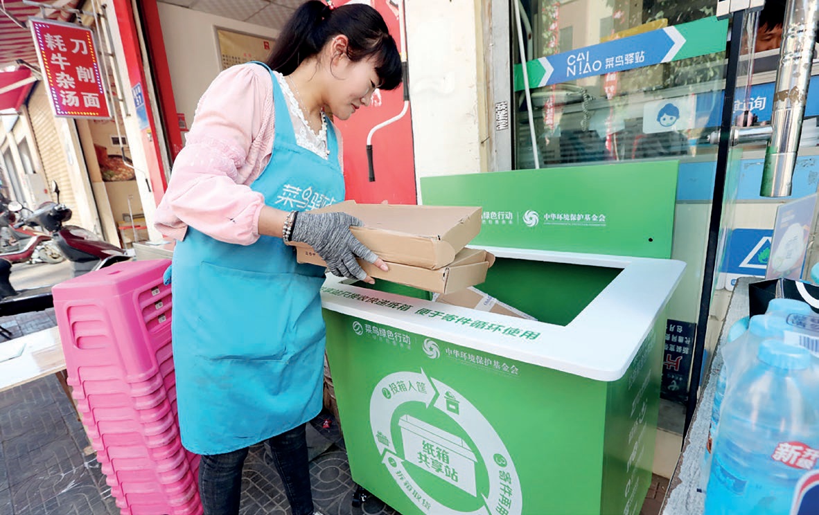 A woman drops empty delivery boxes into a community recycling bin in Kunming, Yunnan province. (China Daily, 2018)